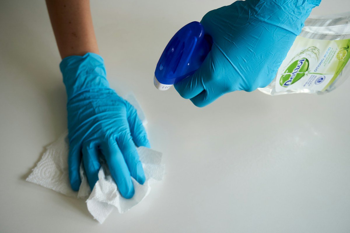 A professional wiping a surface with cleaning supplies